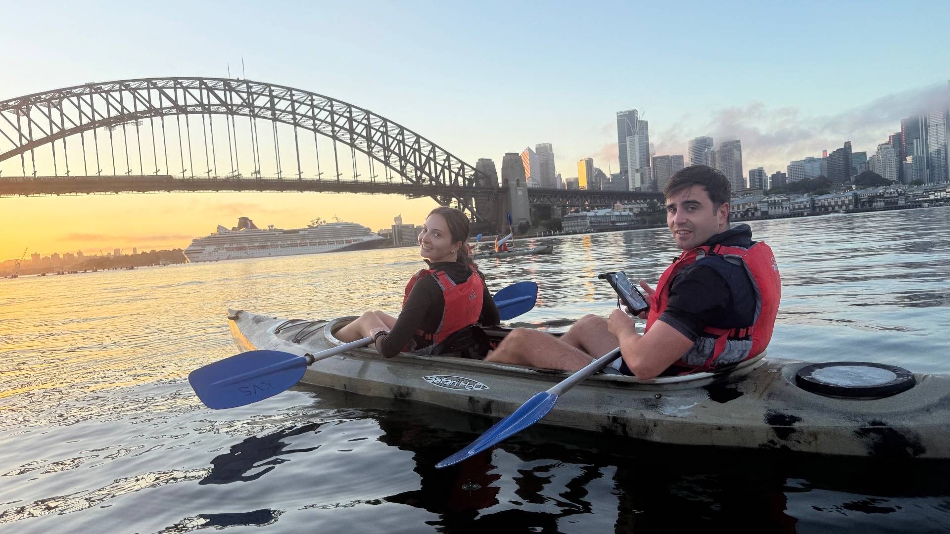 Couple kayaking past cruise ship on Sydney Harbour