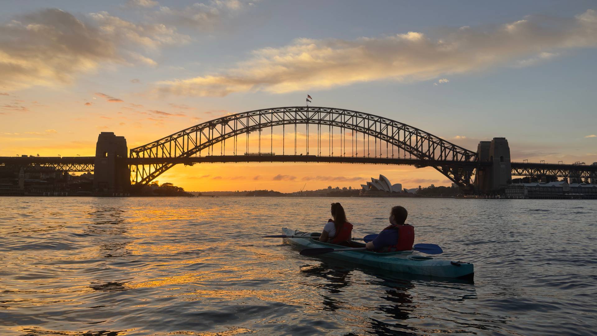 Couple kayaking golden hour Sydney Harbour Bridge views