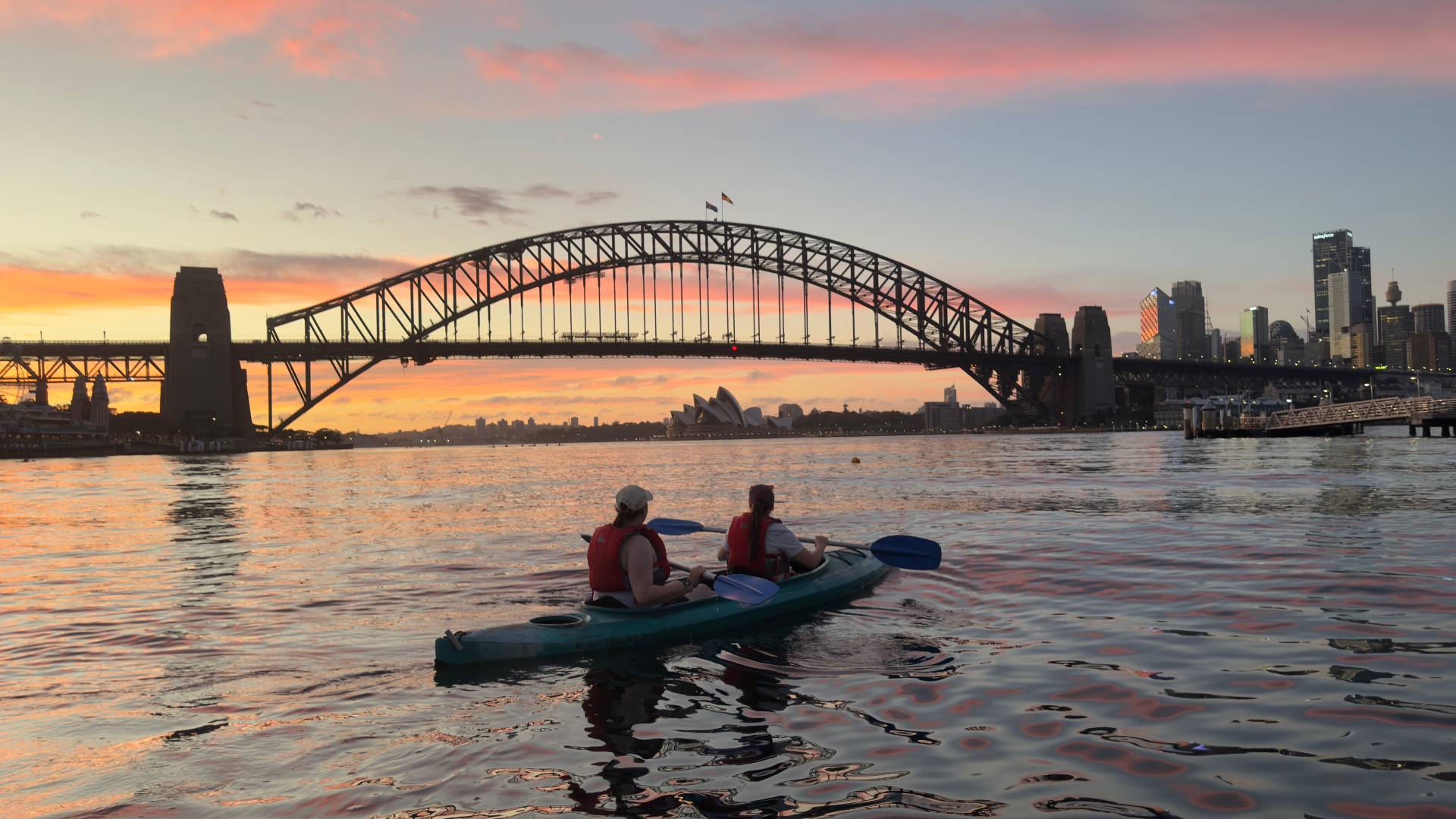 Sydney Kayak Tours couple paddling under pink sunset sky
