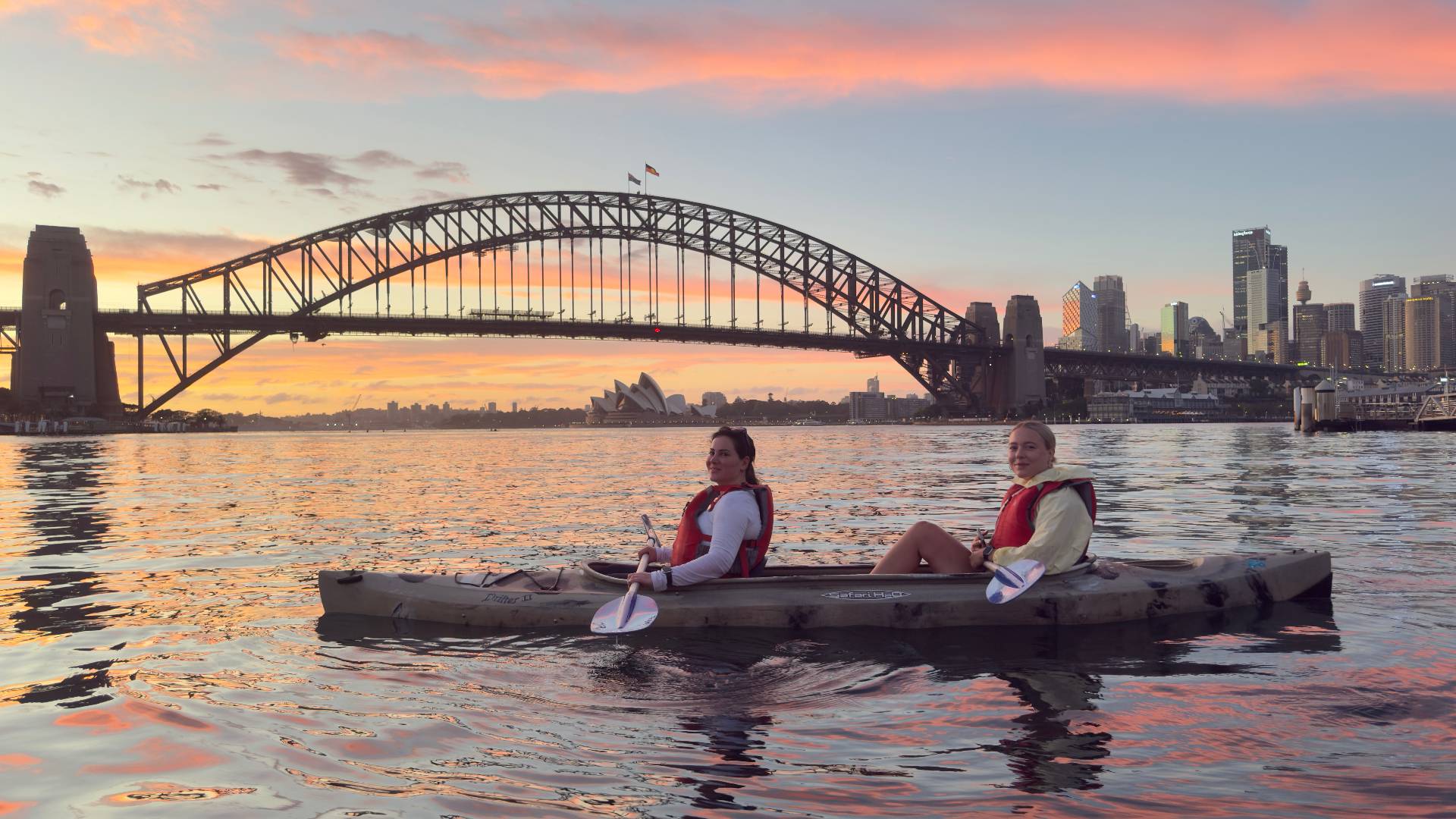 Tandem kayak couple at sunset with Sydney Harbour Bridge
