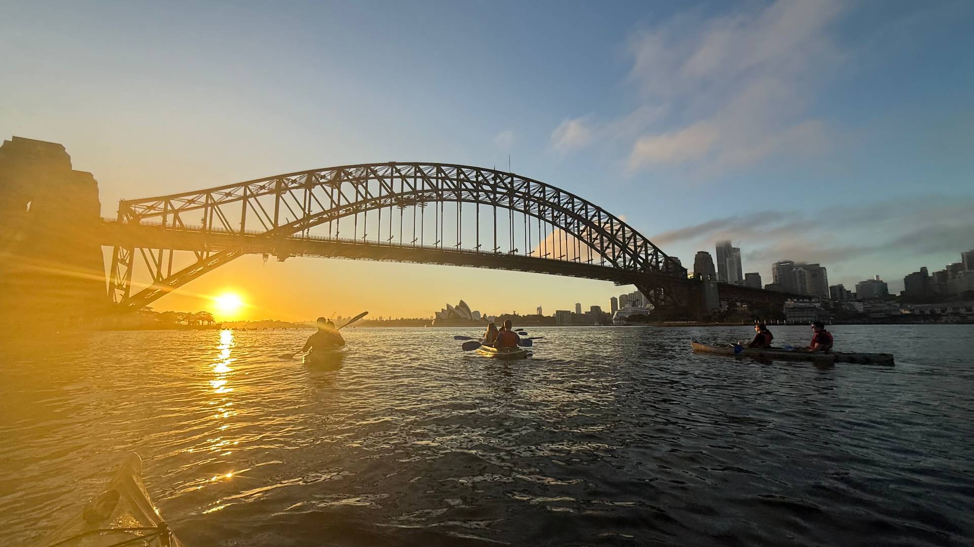 Golden sun flare under Sydney Harbour Bridge during kayak tour