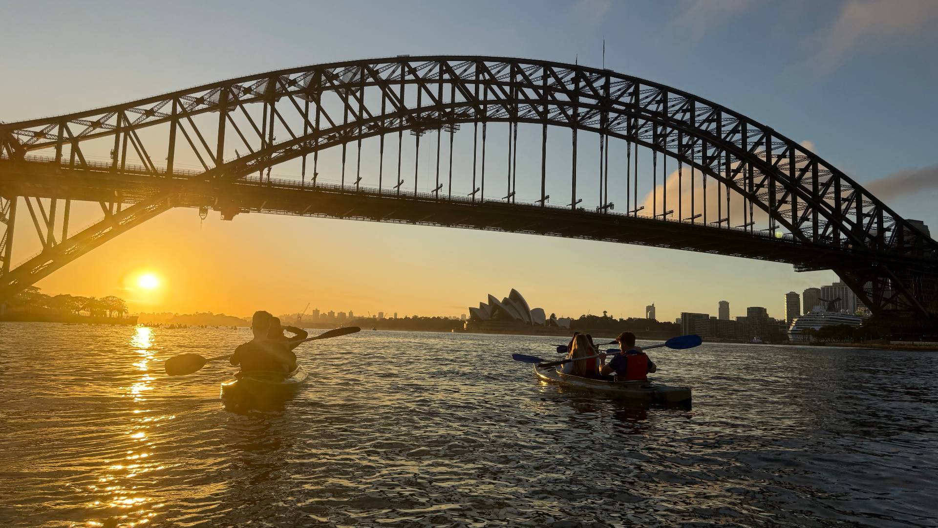 Sydney Kayak Tours group paddling under Harbour Bridge at sunrise
