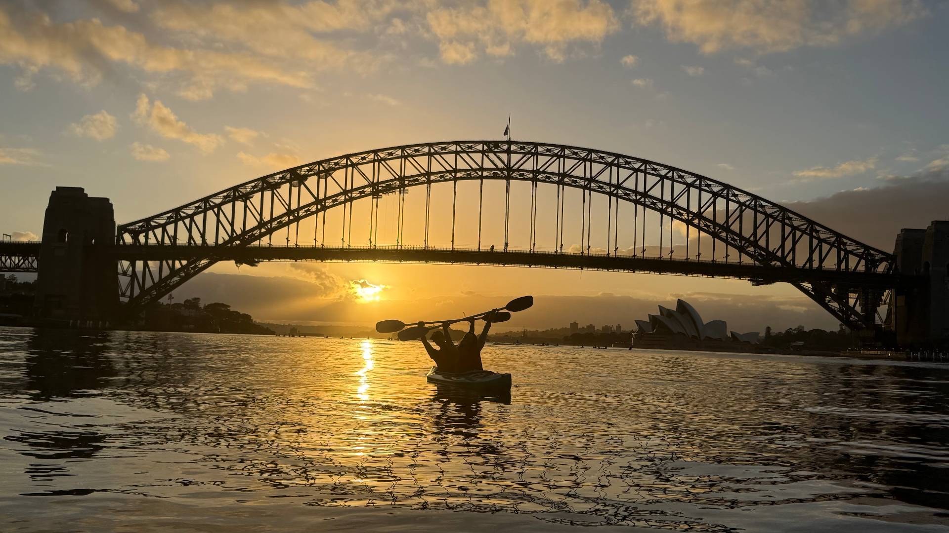Kayaker silhouette under Sydney Harbour Bridge at sunset