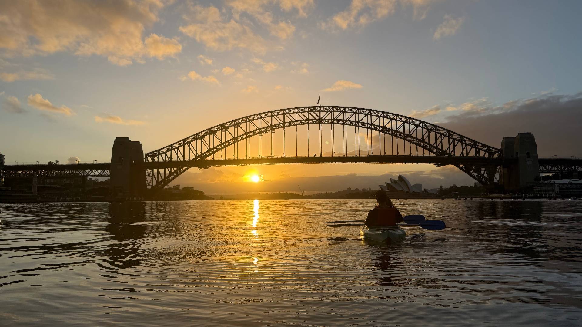 Sunrise kayak tour – solo paddler with golden Sydney Harbour Bridge