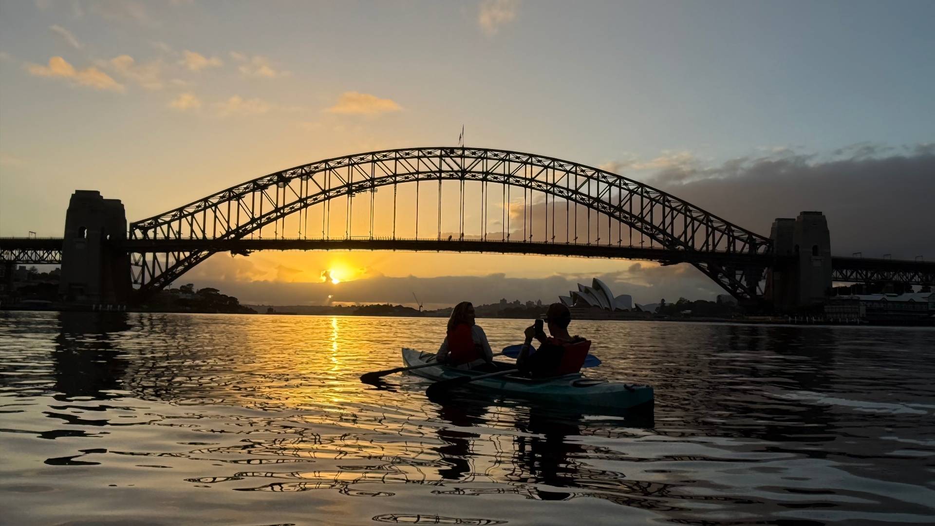Kayaker photographing Sydney Harbour Bridge at sunrise