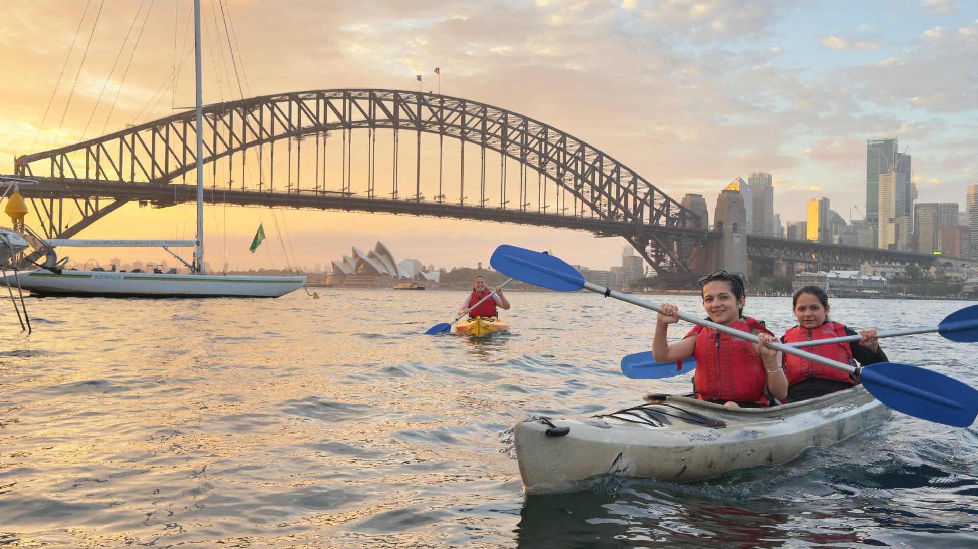 Sydney Kayak Tours – kayakers paddling past sailboats on Sydney Harbour